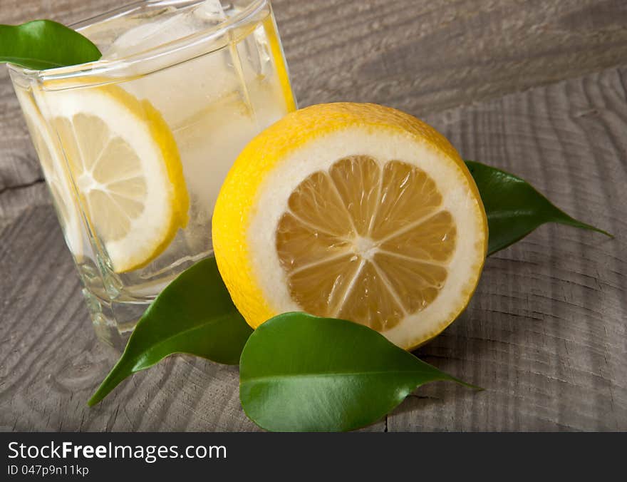 Cocktail glass with lemon and ice on wooden background