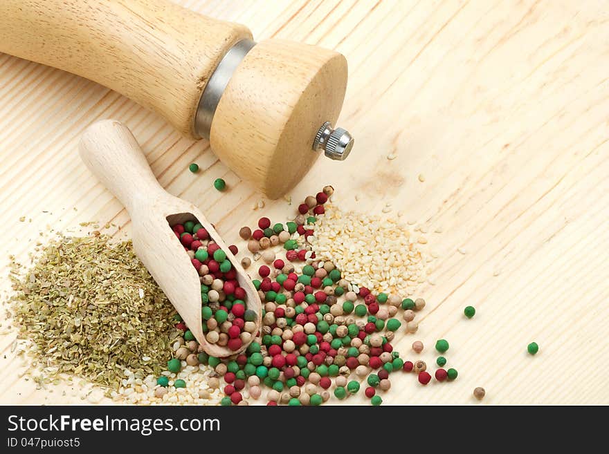 Spice on wooden table: pepper mill, wooden scoop, peppercorn, sesame seeds, dried herbs, top view. Spice on wooden table: pepper mill, wooden scoop, peppercorn, sesame seeds, dried herbs, top view