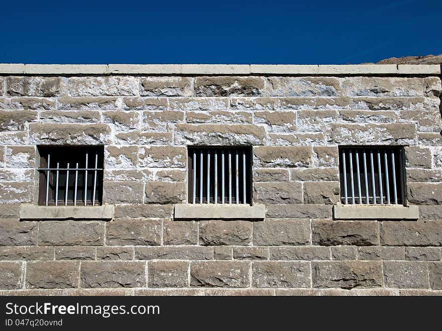 Sandstone wall with the barred windows of a prison. Sandstone wall with the barred windows of a prison