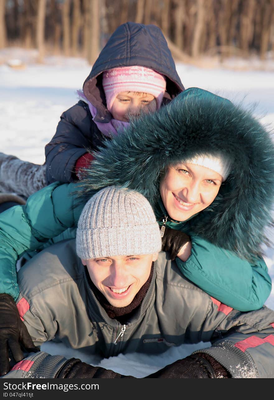 Happy family lying on the snow in the winter