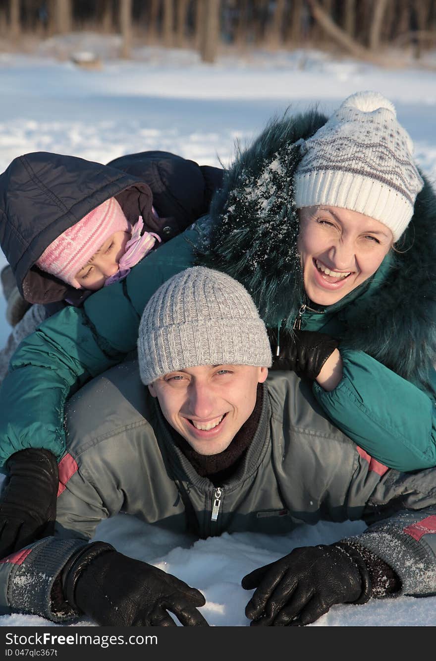 Happy family lying on the snow in the winter