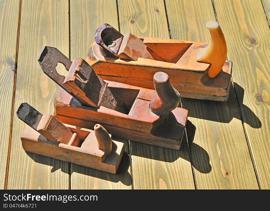 Three old planer made ​​of solid wood lying on a wooden table. Three old planer made ​​of solid wood lying on a wooden table