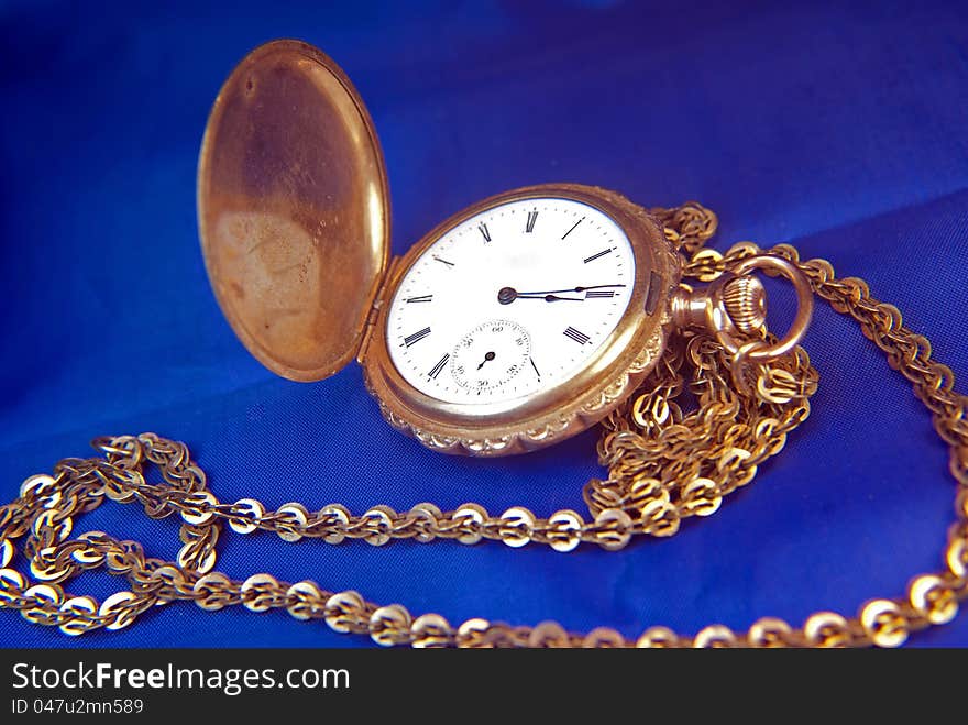 Antique pocket-watch with chain on blue