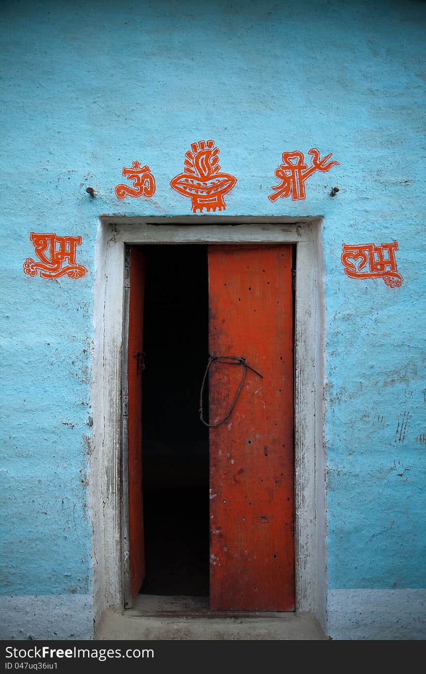 Open door in indian village with well wishing sign related to hinduism on the mud traditional wall. Open door in indian village with well wishing sign related to hinduism on the mud traditional wall