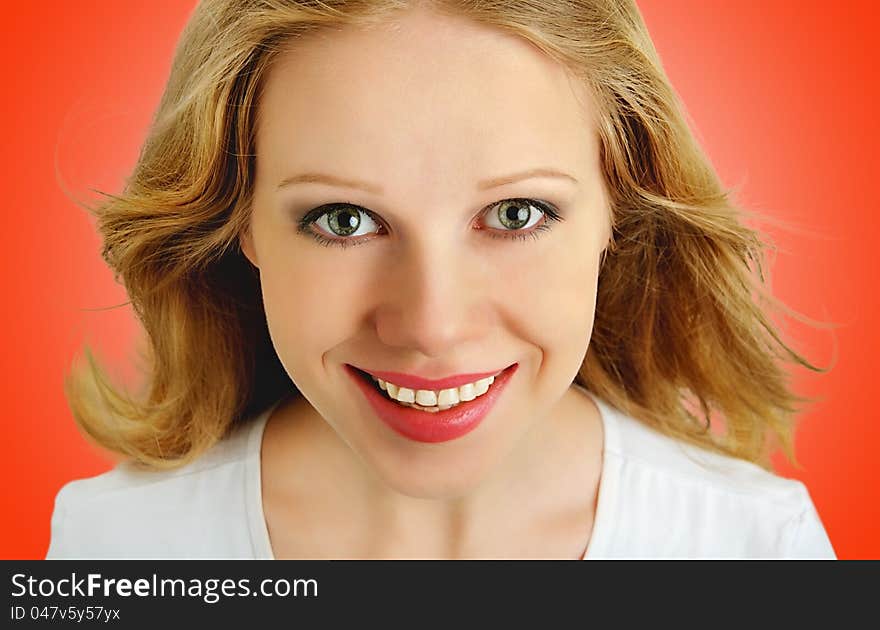 Smiling face of a beautiful girl with flowing hair close up on a red background. Smiling face of a beautiful girl with flowing hair close up on a red background