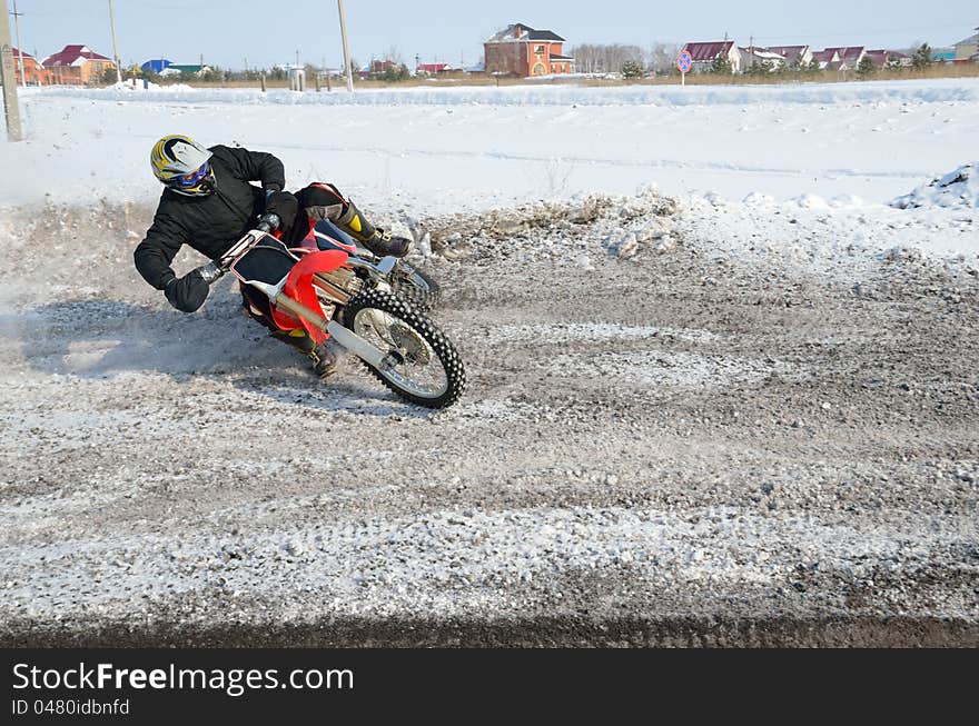 Winter motocross, rider turns the with the slope of the motorcycle and skidding on snowy highway. Winter motocross, rider turns the with the slope of the motorcycle and skidding on snowy highway