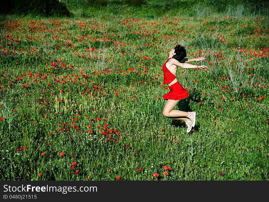 Happy woman jumping in poppy field