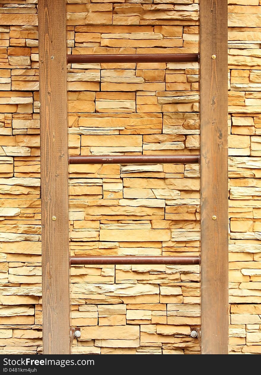 Ladder against the wooden boards of the yellow color