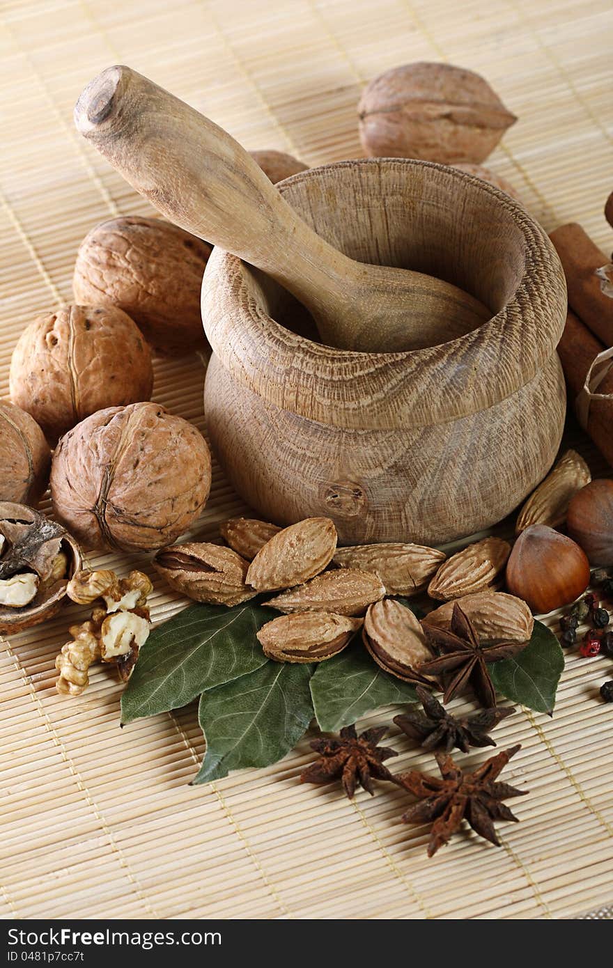 Wooden mortar and pestle with anise, walnut, almond, pepper and bay leaves. Wooden mortar and pestle with anise, walnut, almond, pepper and bay leaves