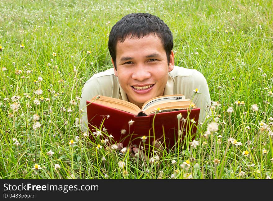 Asian man reading on the field