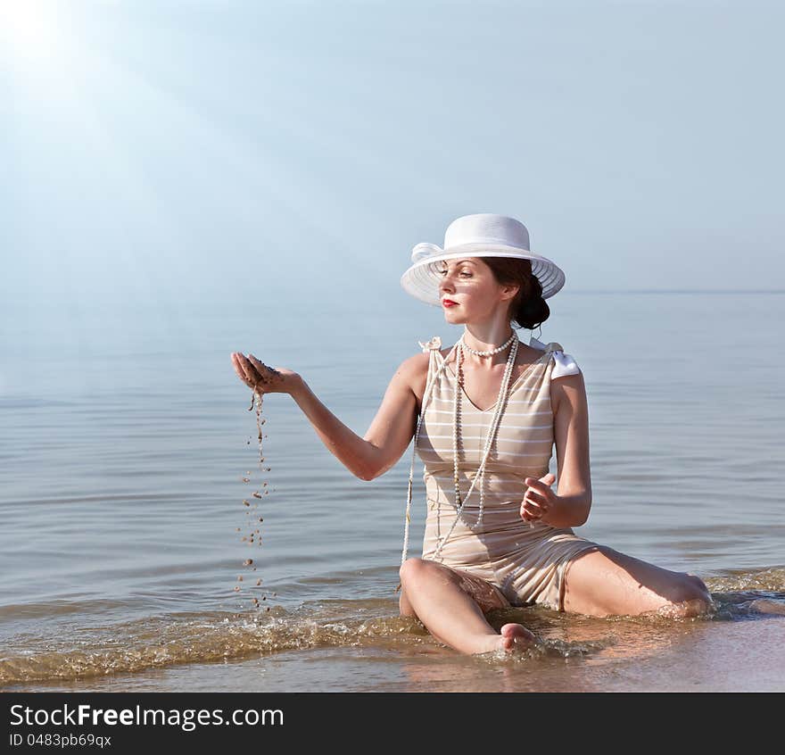 Woman in white hat posing against the sea