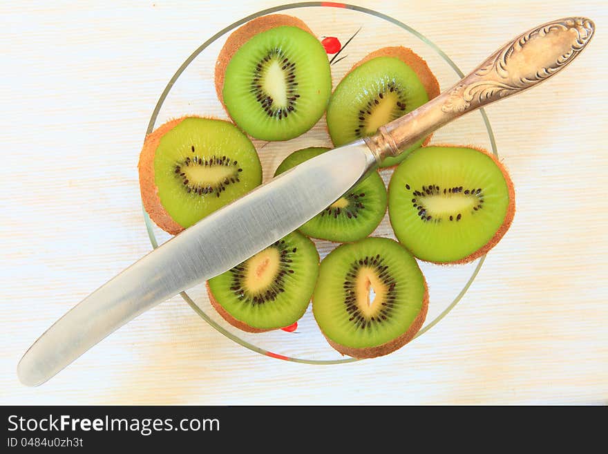 slice of kiwi in TRANSPARENT GLASS vases and knife on the table. slice of kiwi in TRANSPARENT GLASS vases and knife on the table.