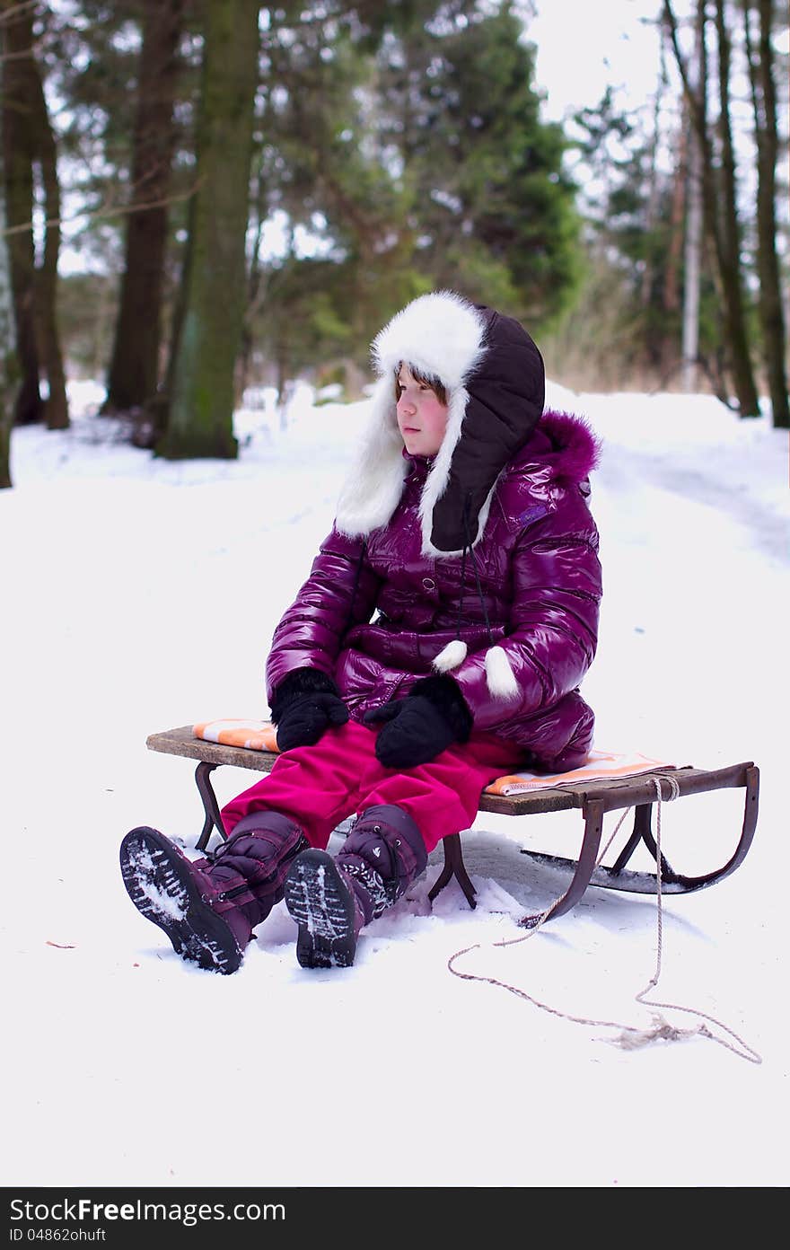 Unhappy kid girl alone in winter forest background