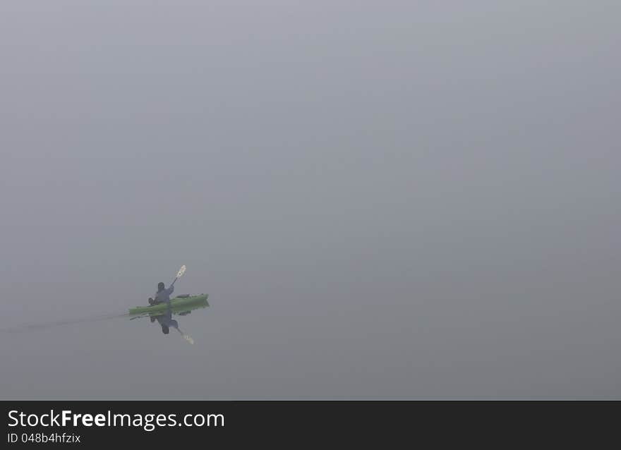 Kayak on a foggy morning paddling into more fog. Kayak on a foggy morning paddling into more fog