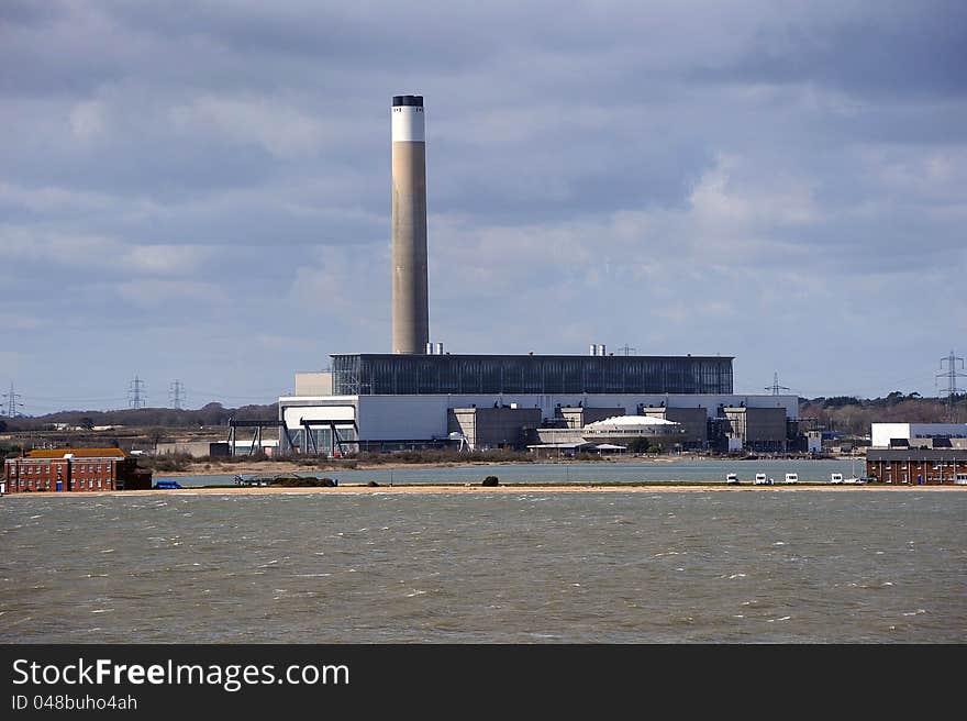 A coastal electricity generating power station against a dark cloudy sky. A coastal electricity generating power station against a dark cloudy sky