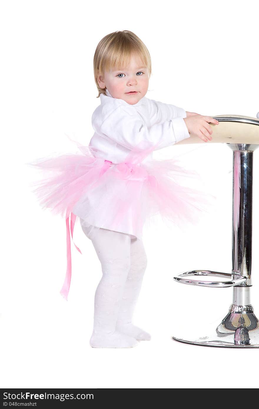 A little girl in a pink tutu standing near bar stool