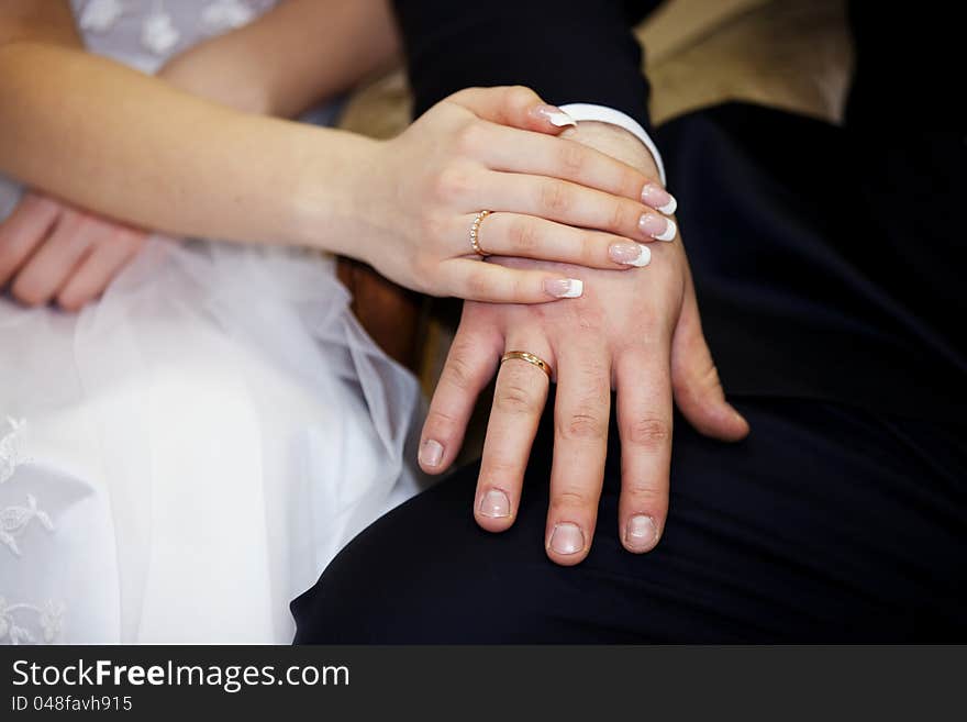 Newlyweds holding hands, their weddingbands showing.