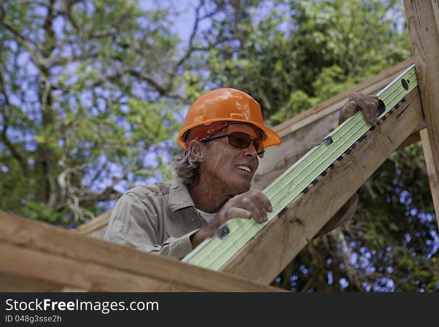 Senior male construction worker building a new house, using a level