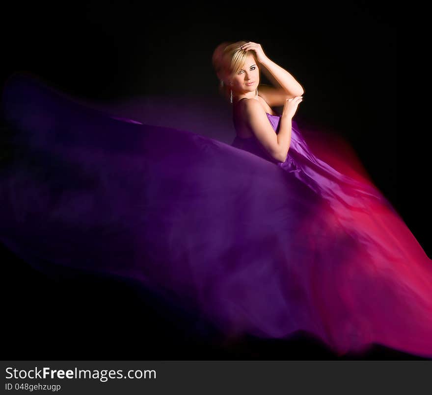 Beautiful blonde in a dress made of fabric flying