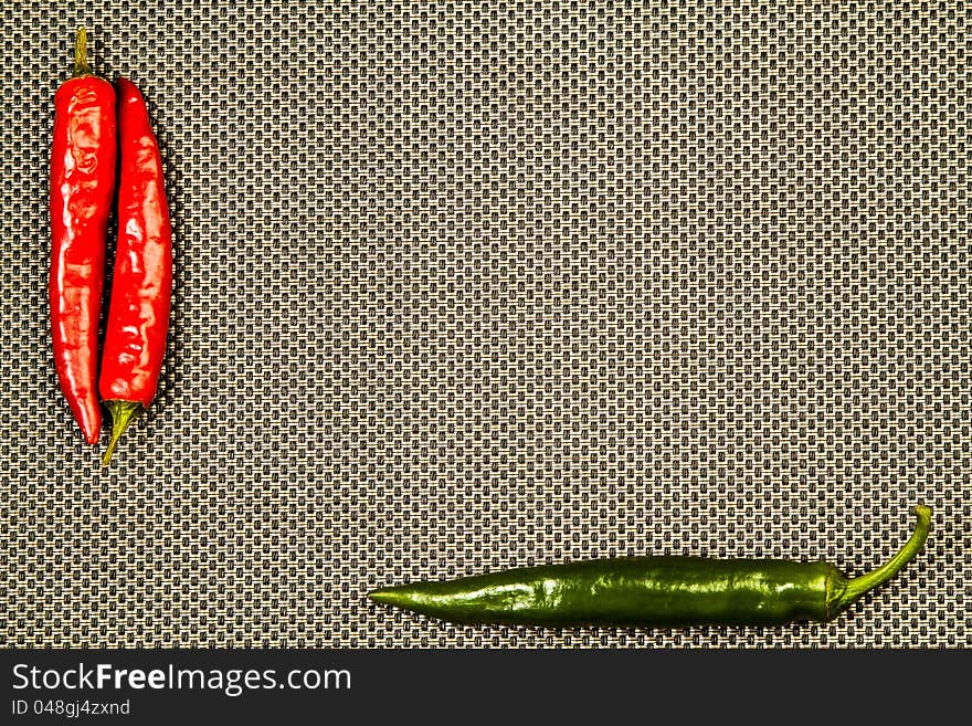 Red and green hot pepper on a beige and black background. Red and green hot pepper on a beige and black background