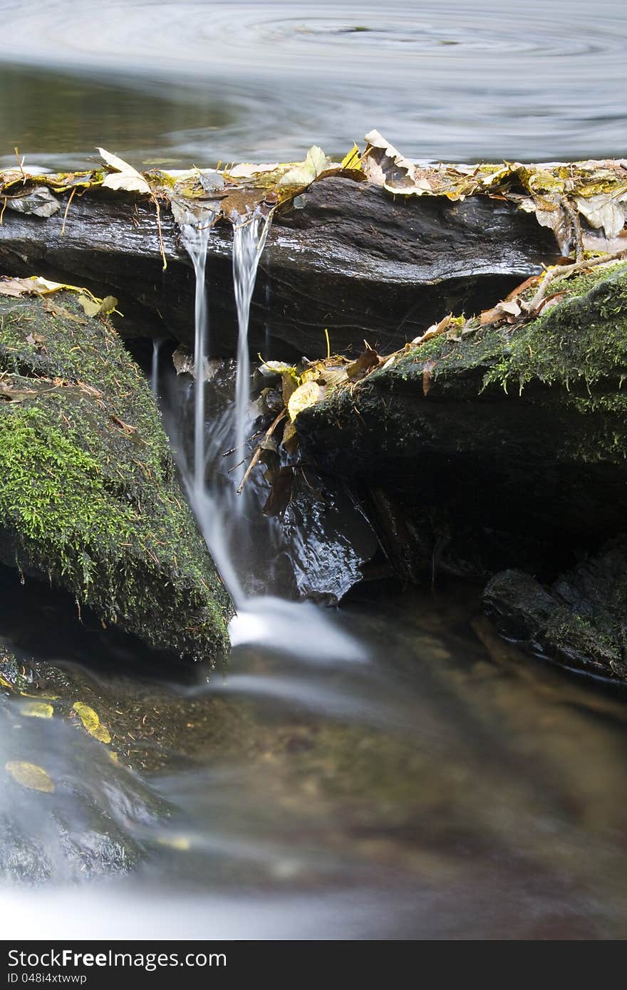 Details of a small weir, water swirl on the stream, the stream dammed stones, stream in the Czech Republic, fallen leaves on the rocks. Details of a small weir, water swirl on the stream, the stream dammed stones, stream in the Czech Republic, fallen leaves on the rocks