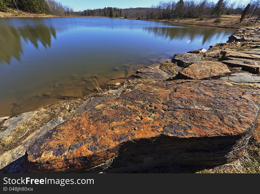 Mountain lake, old rocks and deep blue sky in early spring