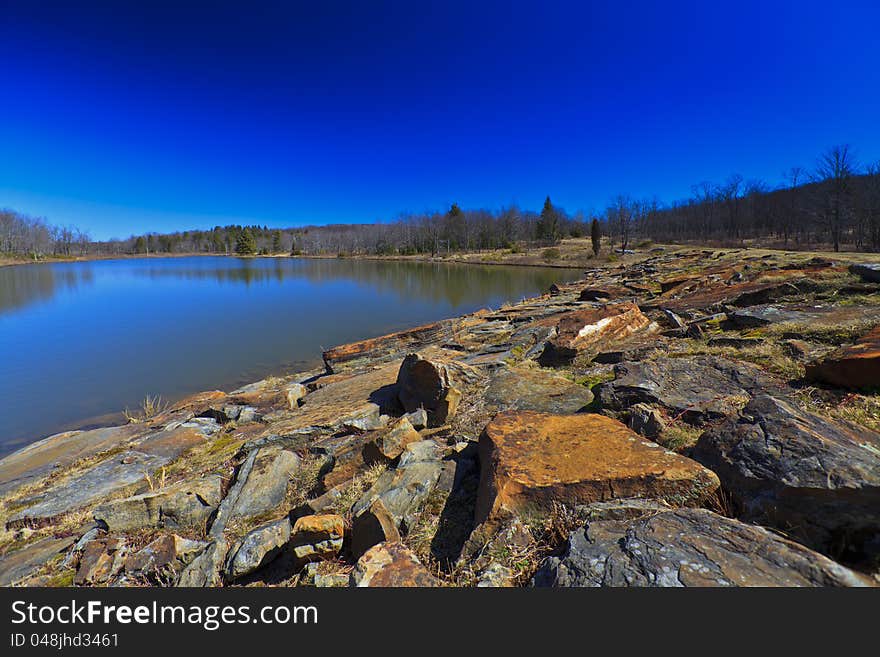 Mountain lake, old rocks and deep blue sky in early spring