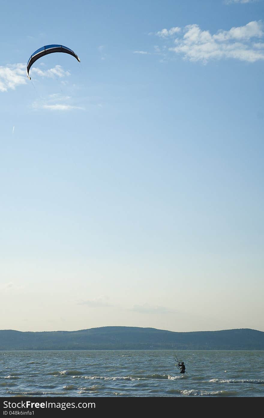 A kite surfer on the lake of Balaton identity is hidden by the blur of his motion. A kite surfer on the lake of Balaton identity is hidden by the blur of his motion.