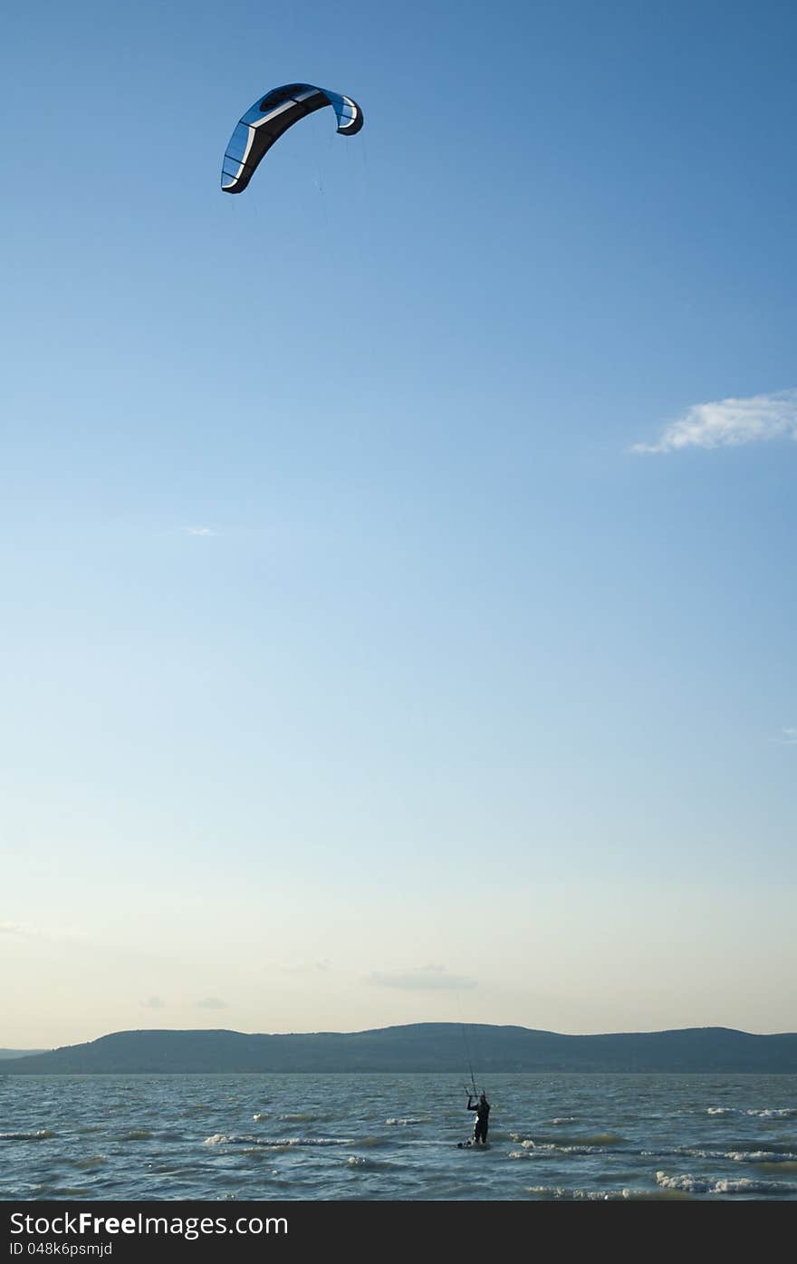 A kite surfer on the lake of Balaton identity is hidden by the blur of his motion. A kite surfer on the lake of Balaton identity is hidden by the blur of his motion.