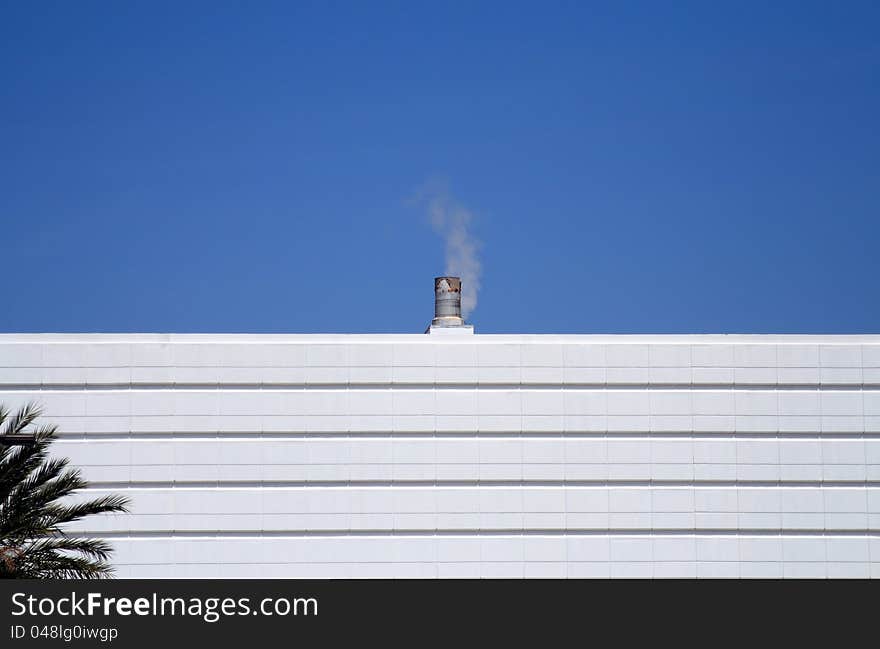 Small Smoke Stack Against A Blue  Sky