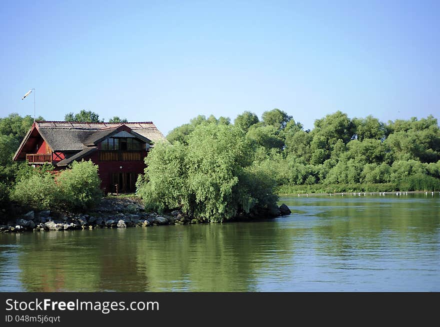 Red house among trees and along a river. Red house among trees and along a river.