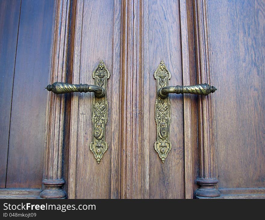 Ornamented front door handles on wooden door. Ornamented front door handles on wooden door