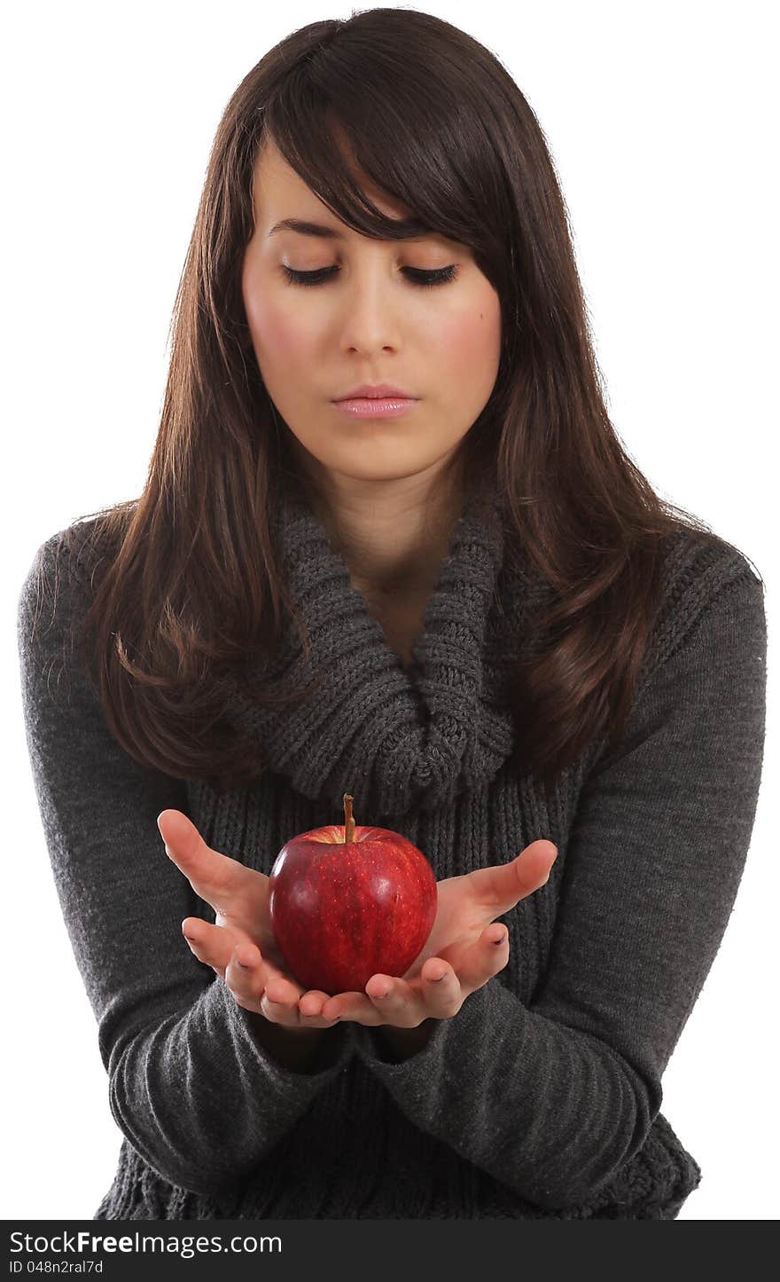 Young and attractive woman is staring at a red apple in her hands. Isolated with clipping path.