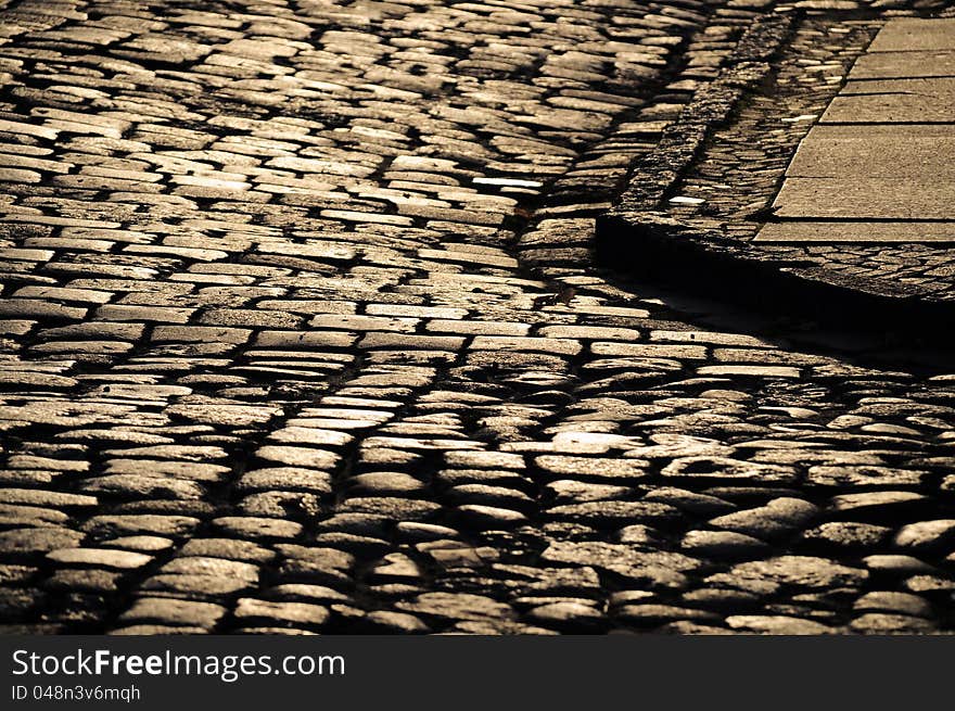 Rough texture of wet cobblestones, old side-street