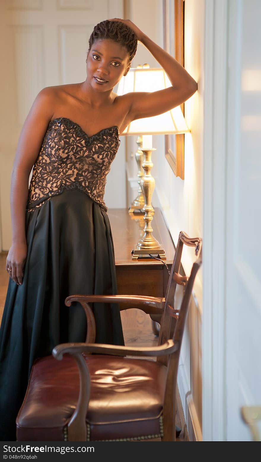 An image of a lovely young African American woman in a long, strapless black dress, standing in a beautiful living room. An image of a lovely young African American woman in a long, strapless black dress, standing in a beautiful living room