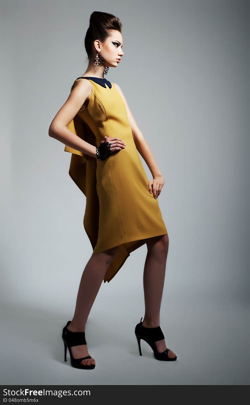 Fashion photo of beautiful stylish woman in yellow trendy dress. Studio shot. Fashion photo of beautiful stylish woman in yellow trendy dress. Studio shot