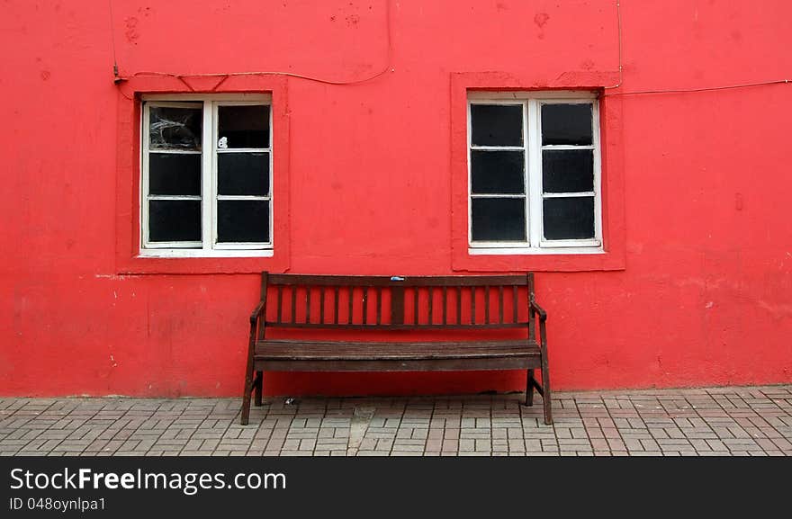 Bench And Two Windows On Red Wall