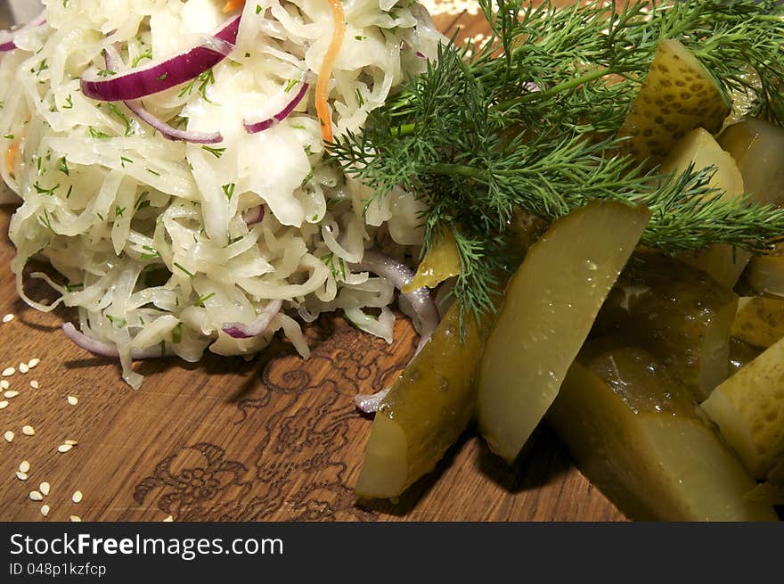 Pickled cabbage, cucumbers, onions on a wooden plate. Pickled cabbage, cucumbers, onions on a wooden plate