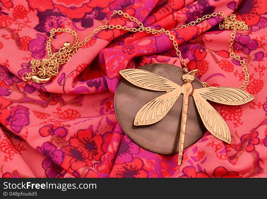 A dragonfly neckless on a red fabric