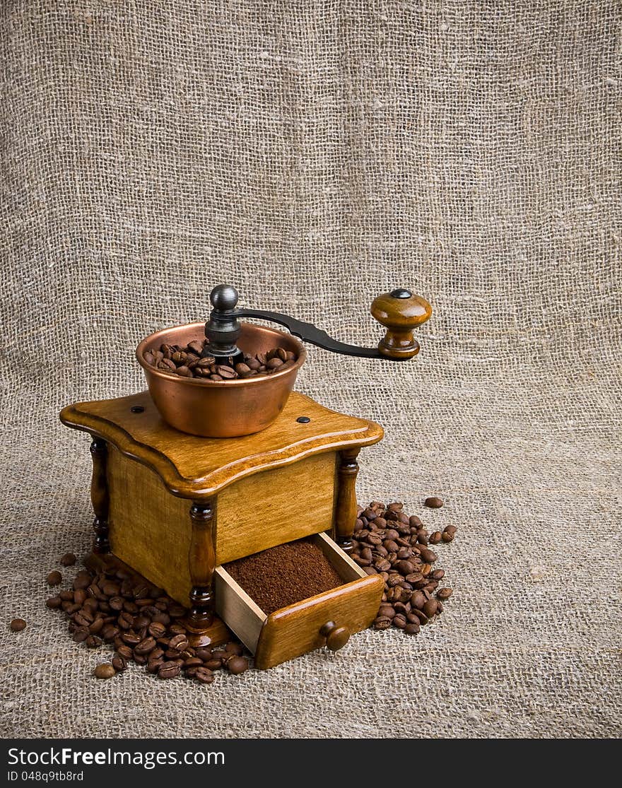 Coffee grinder with coffee beans on sackcloth background