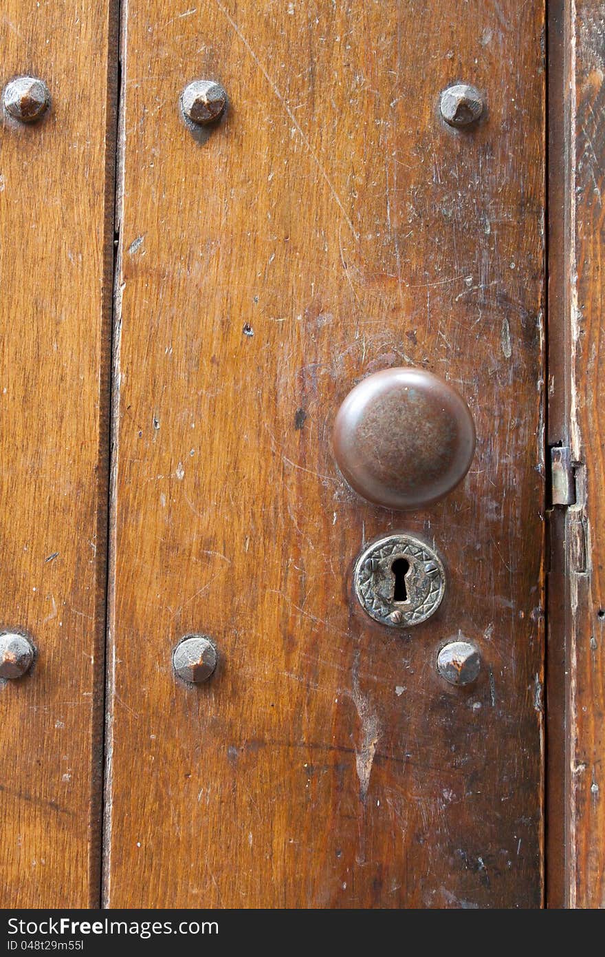 A very old door handle and lock on a vintage wooden building with craftsmanship and originality.