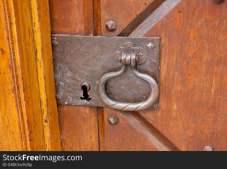 A very old door handle and lock on a vintage wooden building with craftsmanship and originality.