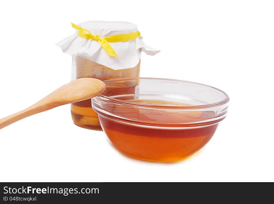 Honey jar with plate and wooden spoon over white