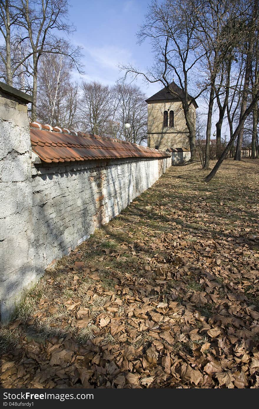 Brick fortification wall in the park, dry fallen leaves on the ground in the park, rychnov park in autumn, fortification wall and a park in sunny day, czech architecture. Brick fortification wall in the park, dry fallen leaves on the ground in the park, rychnov park in autumn, fortification wall and a park in sunny day, czech architecture