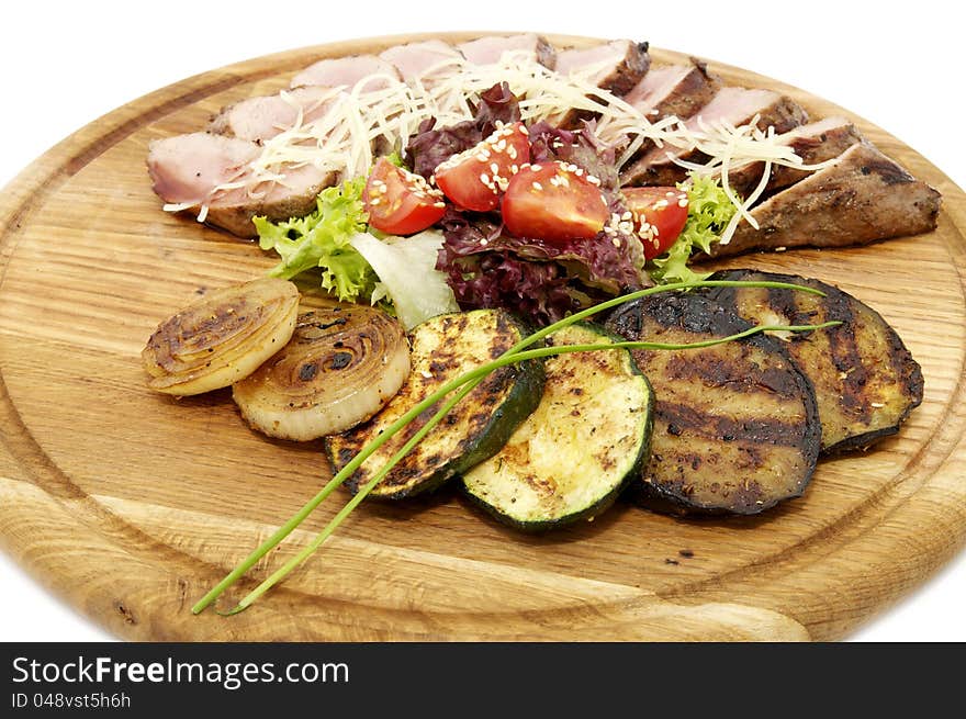 Grilled vegetables and meat on a wooden platter. Grilled vegetables and meat on a wooden platter