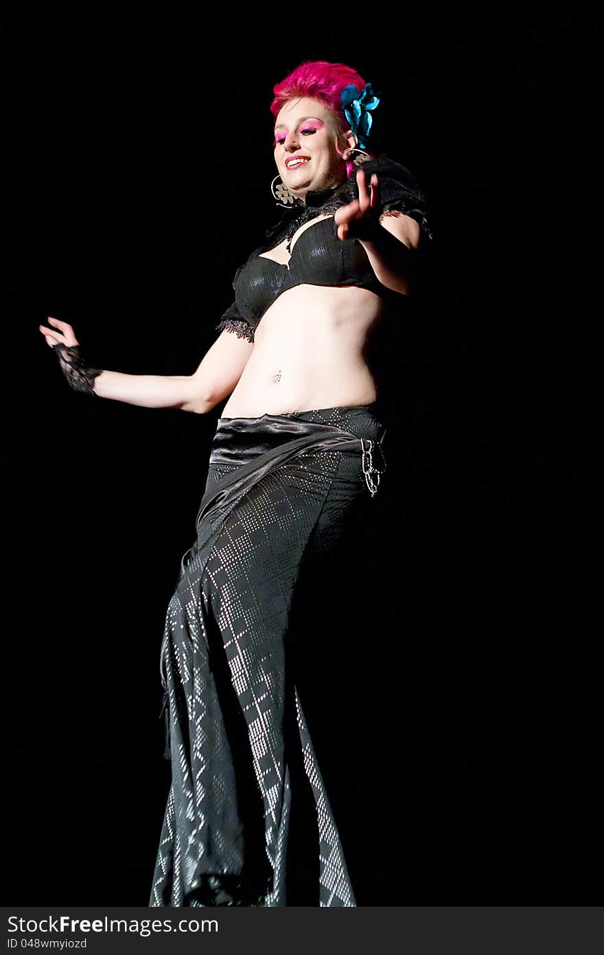 Beautiful red haired belly dancer on black background.