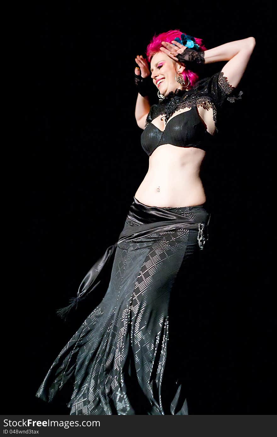 Beautiful red haired belly dancer on black background.