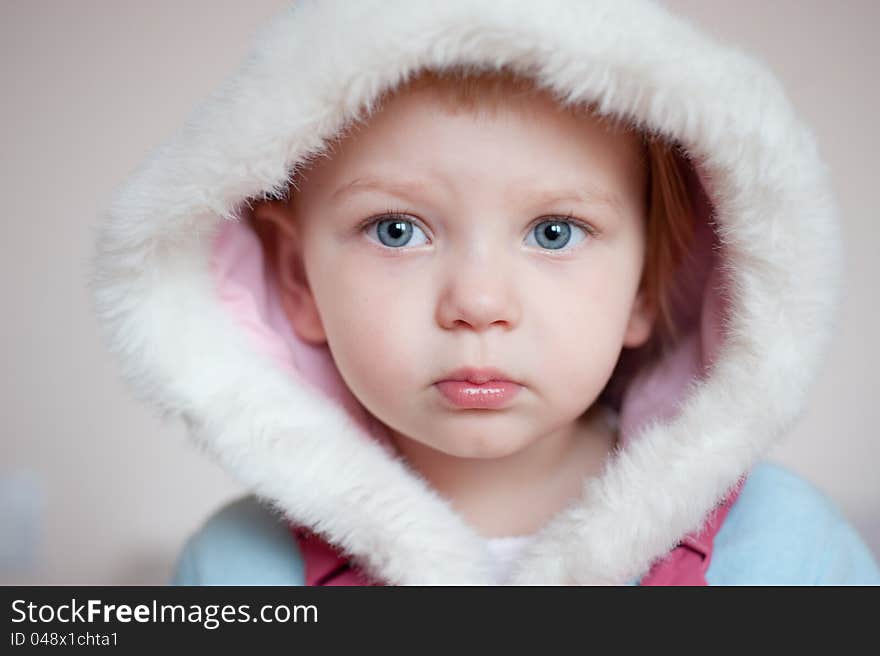 Closeup. Beautiful baby with white hood over gray background. Closeup. Beautiful baby with white hood over gray background