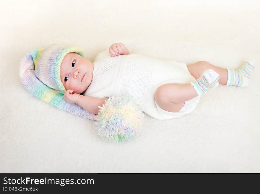 Infant baby dressed funny hat lying on white