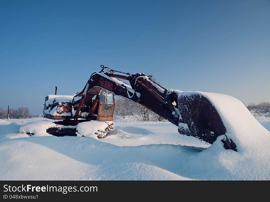 Eexcavator bucket is left to the extended winter in field. Eexcavator bucket is left to the extended winter in field